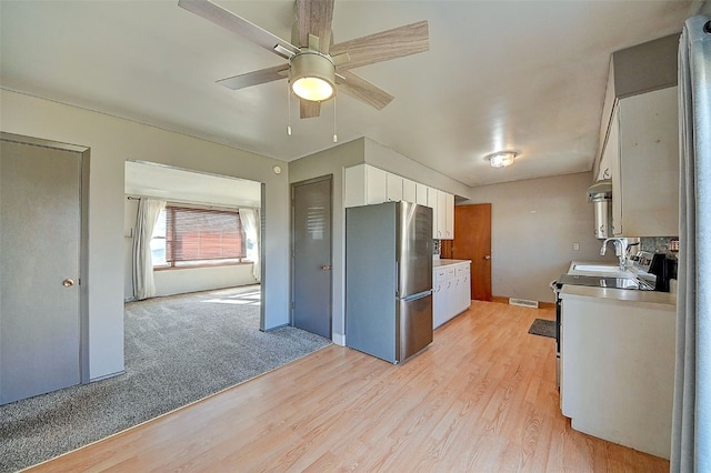 kitchen featuring freestanding refrigerator, range with electric cooktop, light countertops, light wood-style floors, and white cabinetry