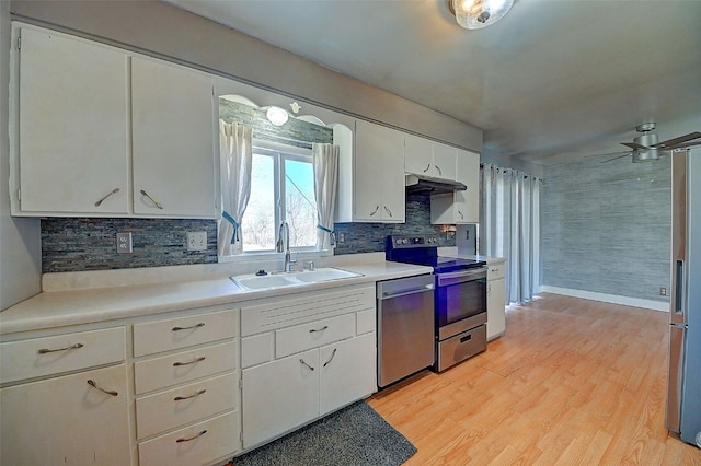 kitchen with light countertops, light wood-style flooring, white cabinets, stainless steel appliances, and a sink