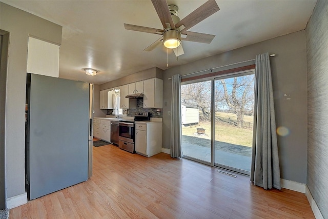 kitchen with under cabinet range hood, light countertops, appliances with stainless steel finishes, light wood-style floors, and white cabinetry