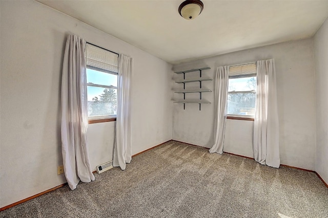 spare room featuring light carpet and baseboards