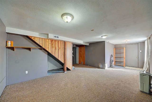 finished below grade area with stairs, carpet flooring, visible vents, and a textured ceiling