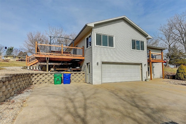 view of property exterior featuring a wooden deck, an attached garage, concrete driveway, and stairs