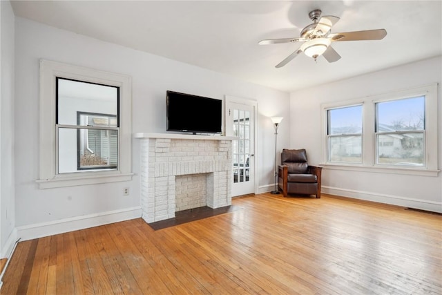 unfurnished living room featuring a fireplace, baseboards, light wood finished floors, and ceiling fan