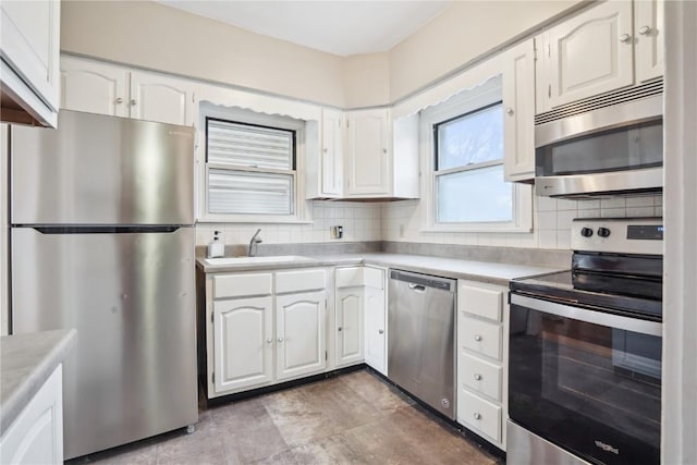 kitchen with tasteful backsplash, light countertops, appliances with stainless steel finishes, white cabinets, and a sink