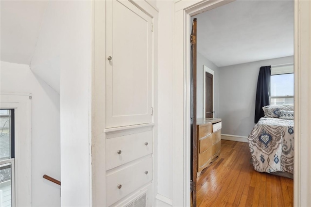 hall featuring vaulted ceiling, light wood-style floors, and baseboards