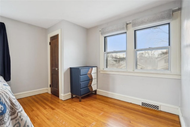 bedroom featuring baseboards, visible vents, and light wood finished floors