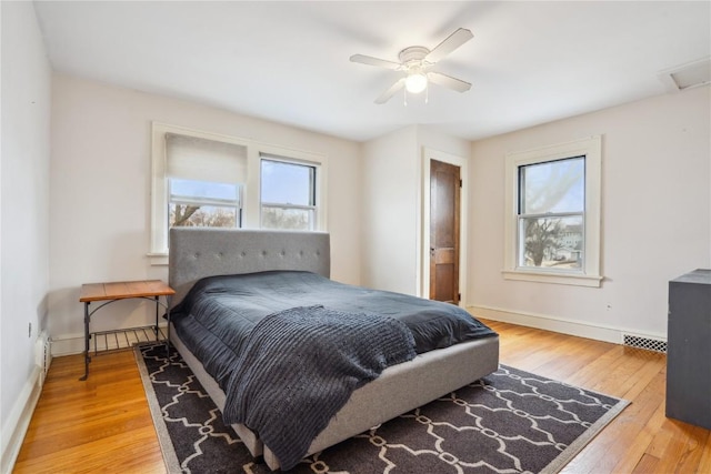 bedroom featuring hardwood / wood-style flooring, baseboards, visible vents, and ceiling fan