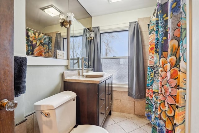 full bath with a wealth of natural light, toilet, tile patterned floors, and vanity