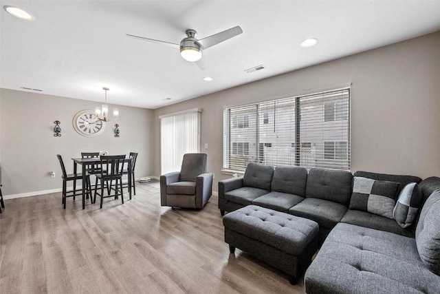 living room with visible vents, baseboards, light wood finished floors, recessed lighting, and ceiling fan with notable chandelier