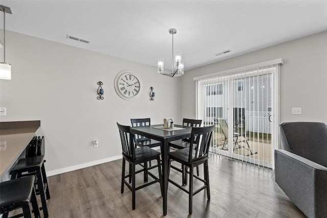 dining space featuring visible vents, baseboards, dark wood-type flooring, and an inviting chandelier