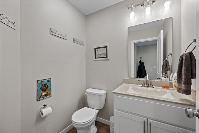 bathroom featuring toilet, vanity, and baseboards