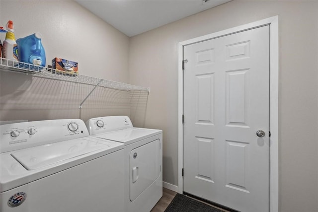 laundry area with laundry area, separate washer and dryer, dark wood-type flooring, and baseboards