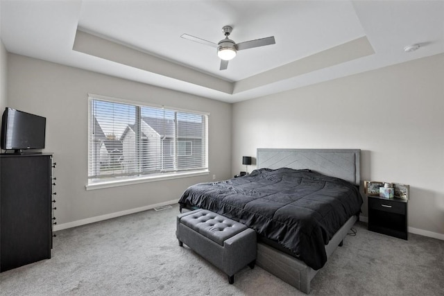 bedroom featuring baseboards, a raised ceiling, carpet, and a ceiling fan