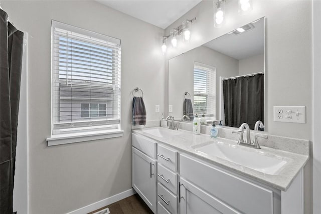 bathroom featuring double vanity, baseboards, visible vents, and a sink