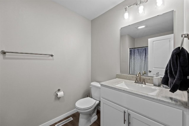 bathroom with vanity, wood finished floors, visible vents, baseboards, and toilet