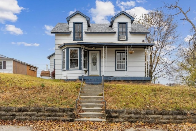 view of front of home with roof with shingles, covered porch, and a front lawn