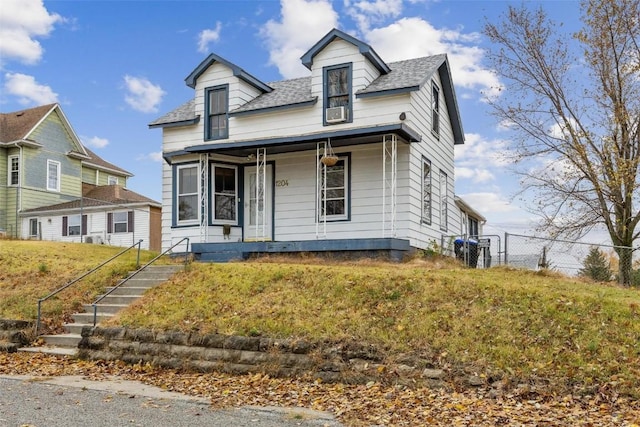 view of front facade featuring a front lawn, fence, covered porch, and roof with shingles