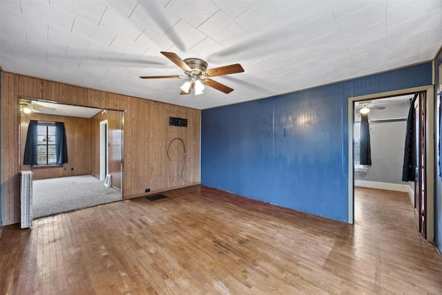 unfurnished room featuring visible vents, radiator heating unit, ceiling fan, and wood finished floors