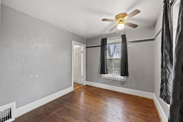 spare room featuring visible vents, ceiling fan, baseboards, and wood-type flooring