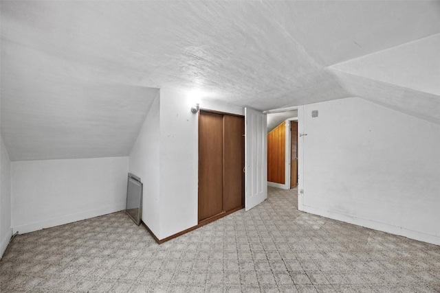 bonus room featuring baseboards, a textured ceiling, and lofted ceiling