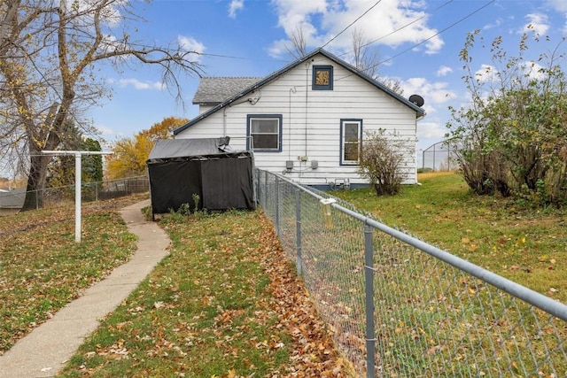 view of side of property featuring a storage unit, a fenced backyard, a yard, and an outdoor structure