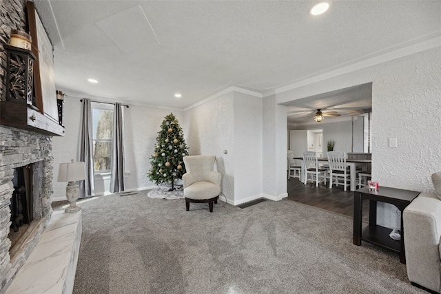 living room featuring ornamental molding, a textured ceiling, a stone fireplace, baseboards, and a textured wall