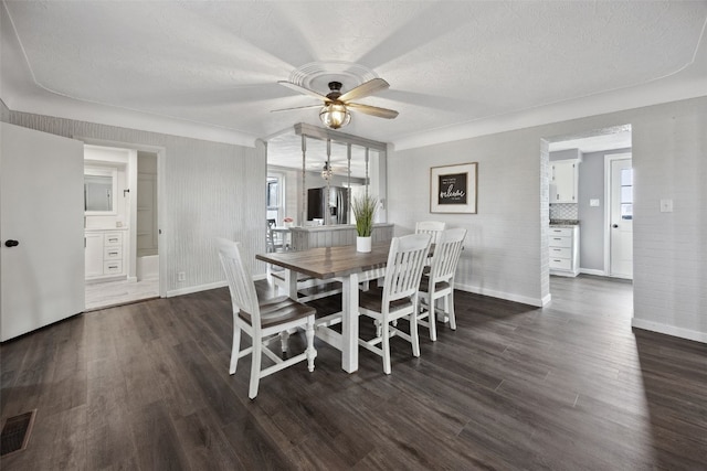 dining area with visible vents, dark wood-type flooring, baseboards, ceiling fan, and a textured ceiling