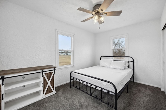 carpeted bedroom with ceiling fan, baseboards, and a textured wall