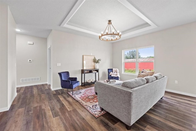 living room featuring a tray ceiling, dark wood-style floors, visible vents, and baseboards