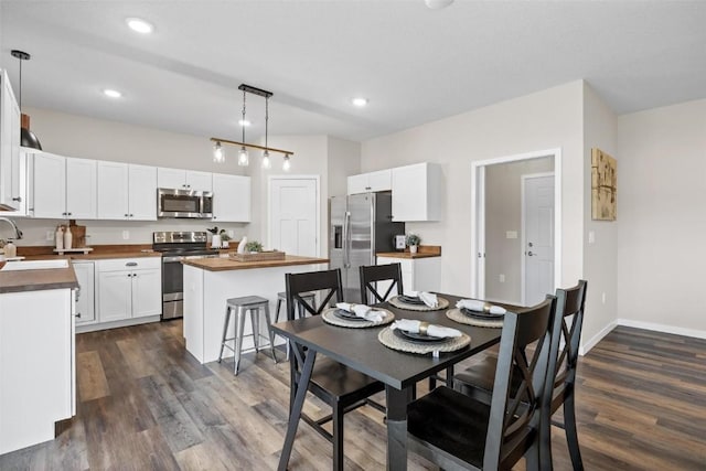 kitchen with wood counters, dark wood finished floors, a center island, white cabinetry, and stainless steel appliances