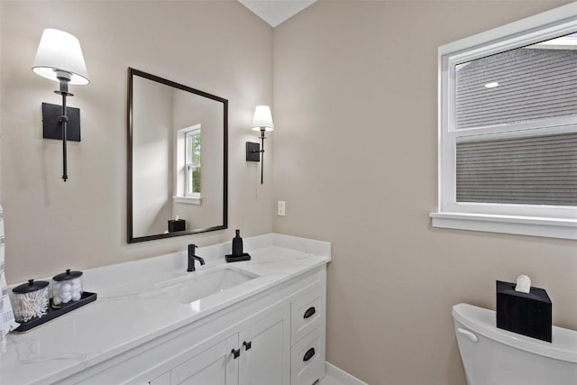 half bath with vanity, toilet, and baseboards