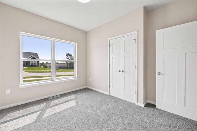 unfurnished bedroom featuring a closet, carpet flooring, baseboards, and visible vents