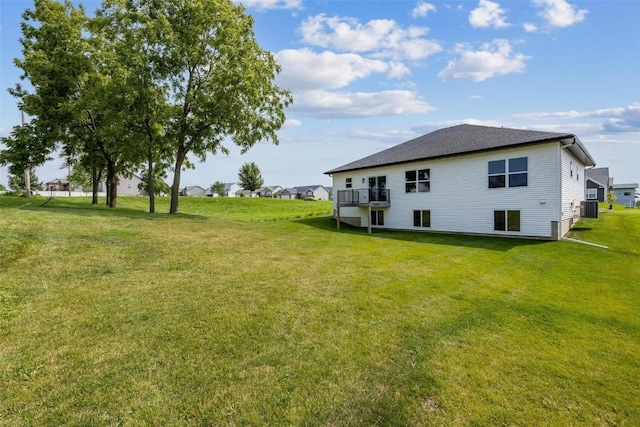 back of property with central AC unit and a lawn