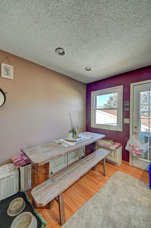 dining area with light wood-style flooring and a textured ceiling