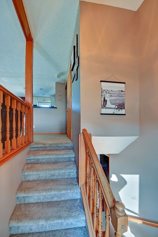 stairway featuring a textured ceiling