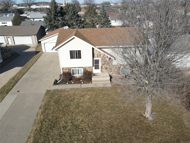 view of front of property with a garage, stone siding, a front lawn, and a shingled roof