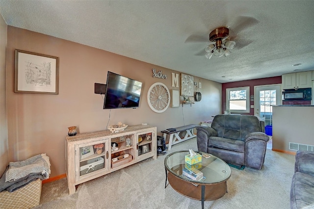 carpeted living room featuring visible vents, ceiling fan, a textured ceiling, and baseboards