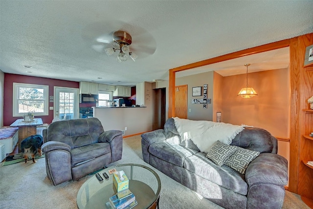 living area with a textured ceiling, ceiling fan, baseboards, and light carpet