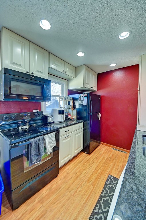 kitchen featuring light wood-style flooring, recessed lighting, black appliances, a textured ceiling, and white cabinetry