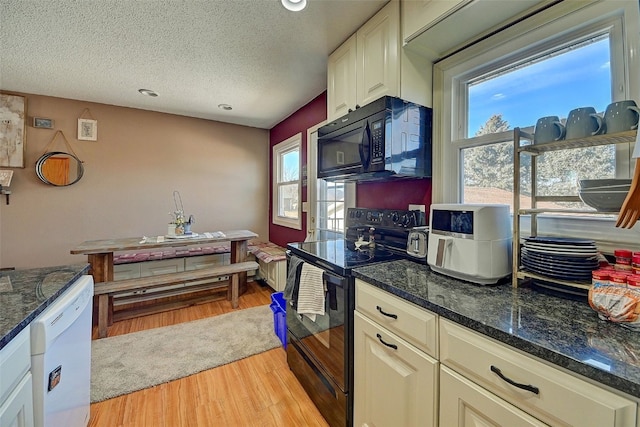 kitchen featuring black appliances, light wood-style flooring, dark stone countertops, a textured ceiling, and white cabinetry