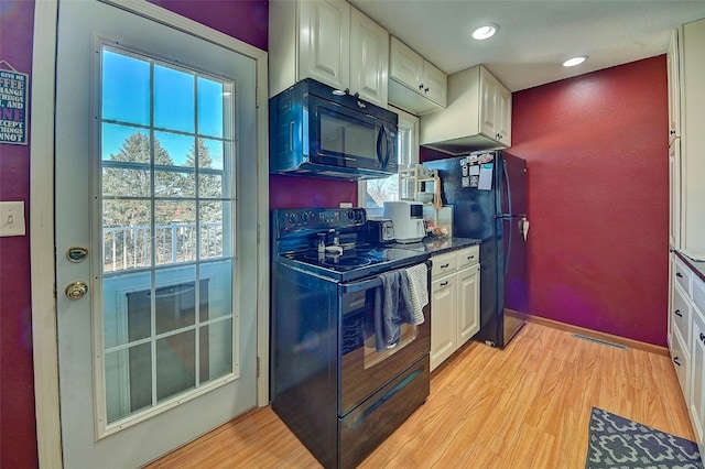 kitchen featuring black appliances, light wood-style flooring, and white cabinetry