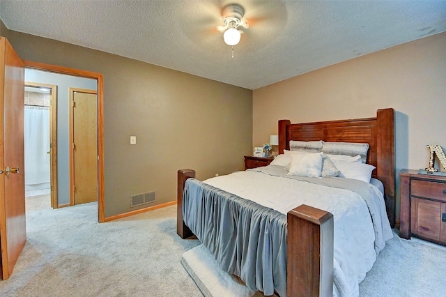 bedroom with a ceiling fan, baseboards, visible vents, a textured ceiling, and light colored carpet