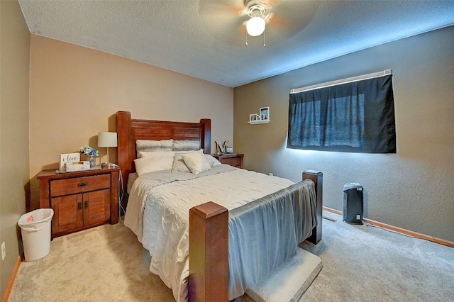 bedroom with light carpet, baseboards, a textured ceiling, and a ceiling fan