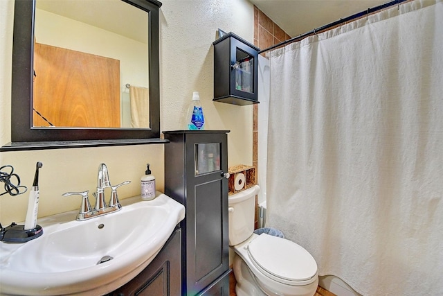 bathroom featuring a shower with shower curtain, toilet, vanity, and a textured wall