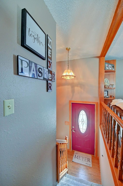 entryway featuring stairway, a textured ceiling, and wood finished floors