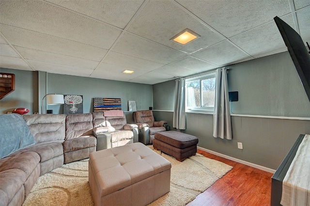 living area featuring wood finished floors, baseboards, and a drop ceiling