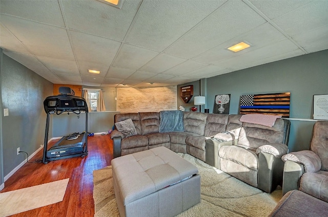 living area featuring wood finished floors, baseboards, and a drop ceiling