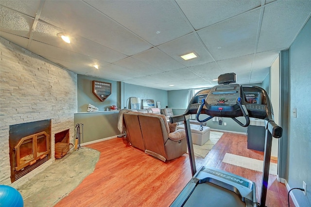 workout room featuring a fireplace, wood finished floors, baseboards, and a paneled ceiling