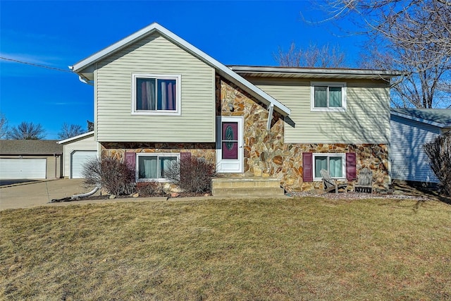 split foyer home with a front lawn, concrete driveway, a garage, an outbuilding, and stone siding