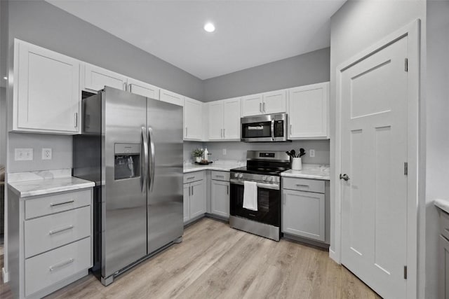 kitchen featuring white cabinetry, appliances with stainless steel finishes, gray cabinetry, and light wood finished floors